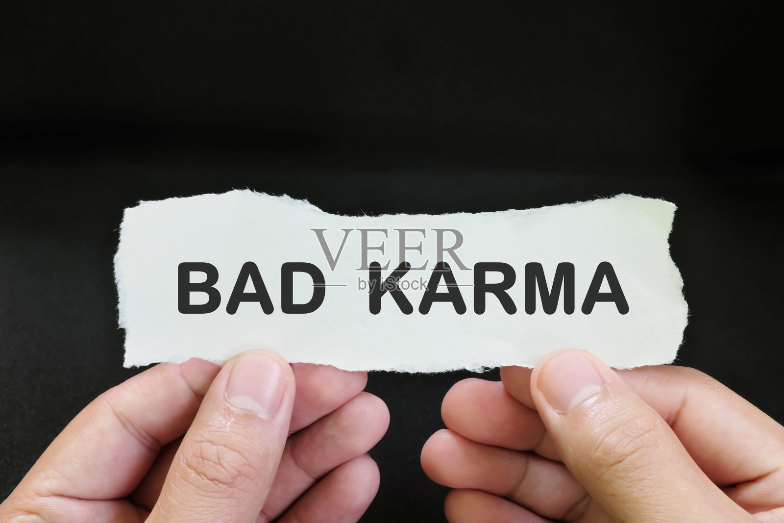 人的手拿着一张纸,上面写着黑色背景的恶业。照片摄影图片