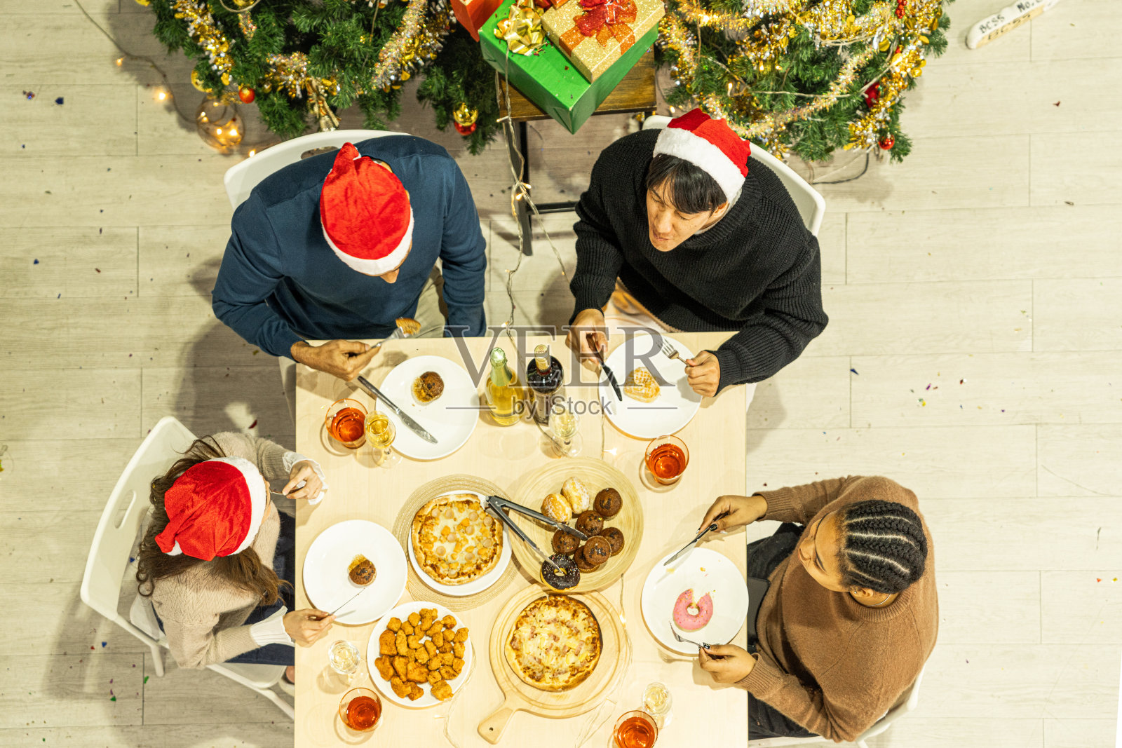 亚洲朋友男女庆祝的俯视图。一个女人在桌子上端着披萨,还有零食和饮料。快乐朋友平安夜庆祝宴会美食和香槟酒。照片摄影图片