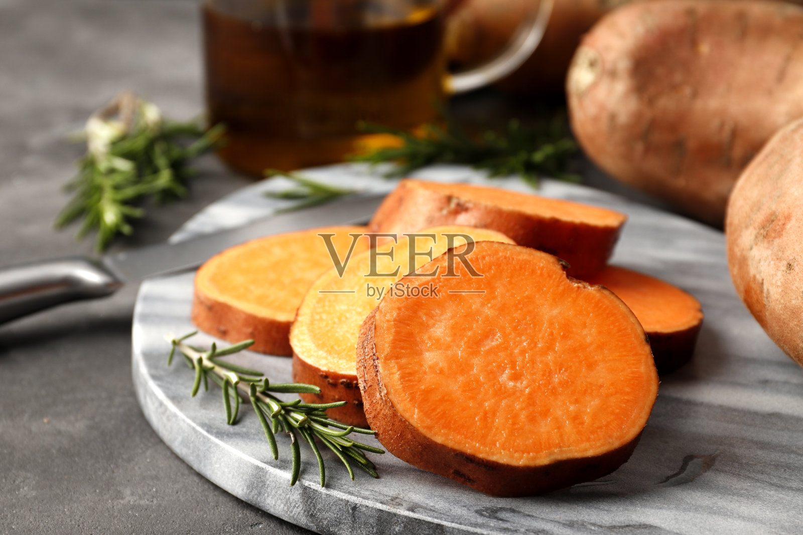 由新鲜的红薯片、迷迭香香料、菜刀和菜油组成的特写镜头。照片摄影图片