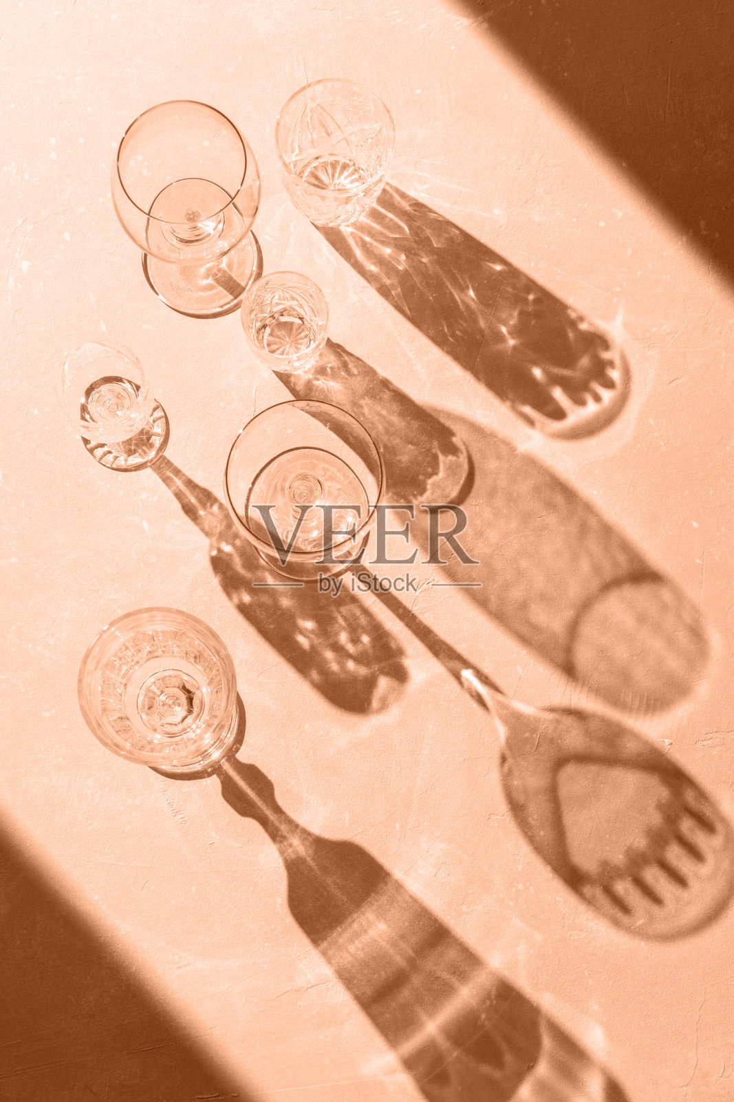 各种各样的空杯子在桃色背景与时尚硬阴影和阳光。阴影叠加效果。桃色柔色潘通2024年时尚平铺。照片摄影图片