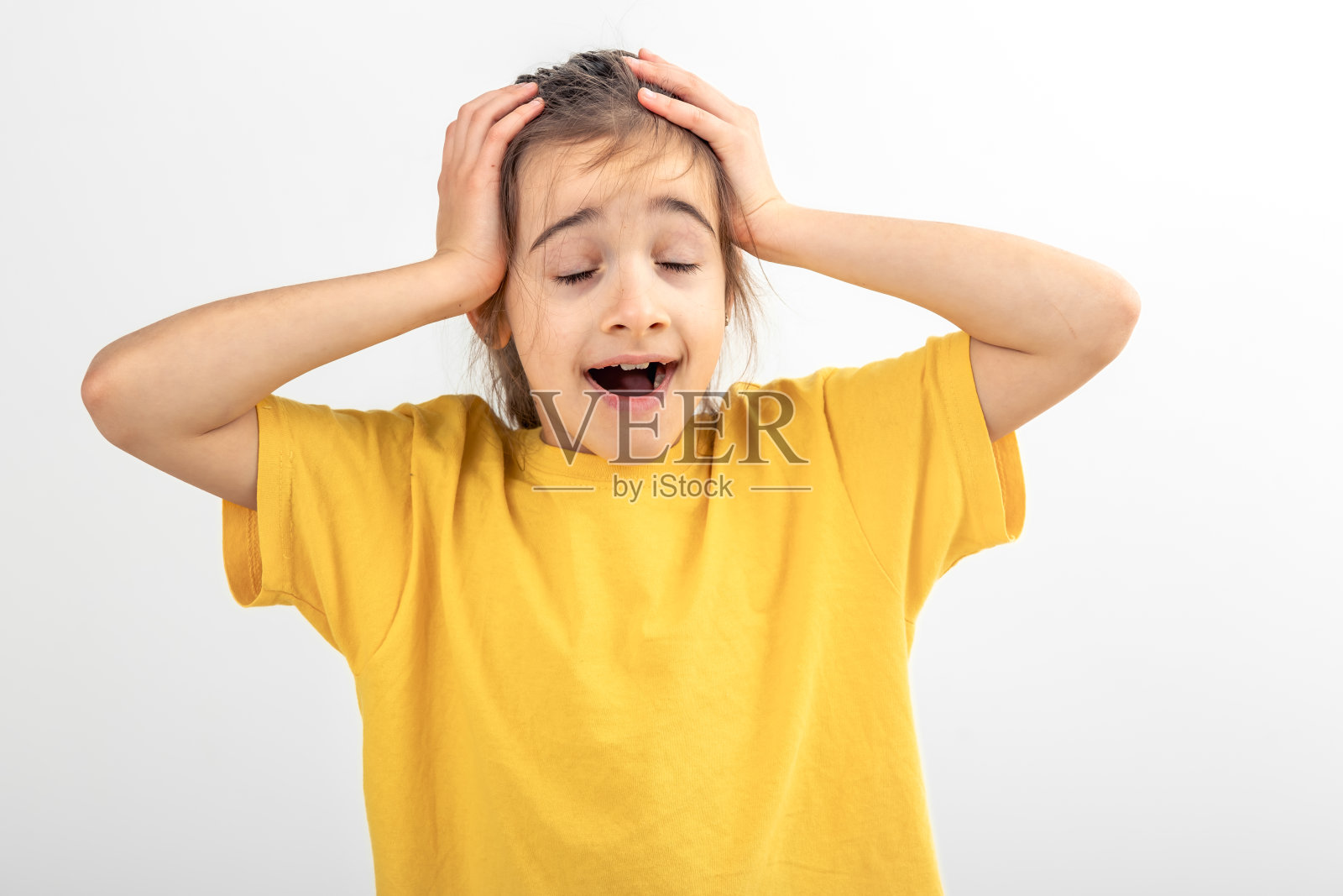 穿着黄色t恤的白人小女孩把头放在白底上。照片摄影图片