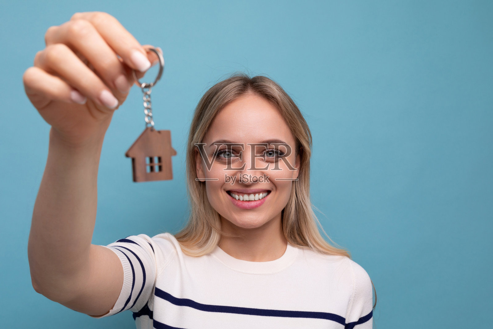 一个快乐的年轻女子的横向照片,她抵押贷款买了一套公寓,背景是蓝色孤立的照片摄影图片