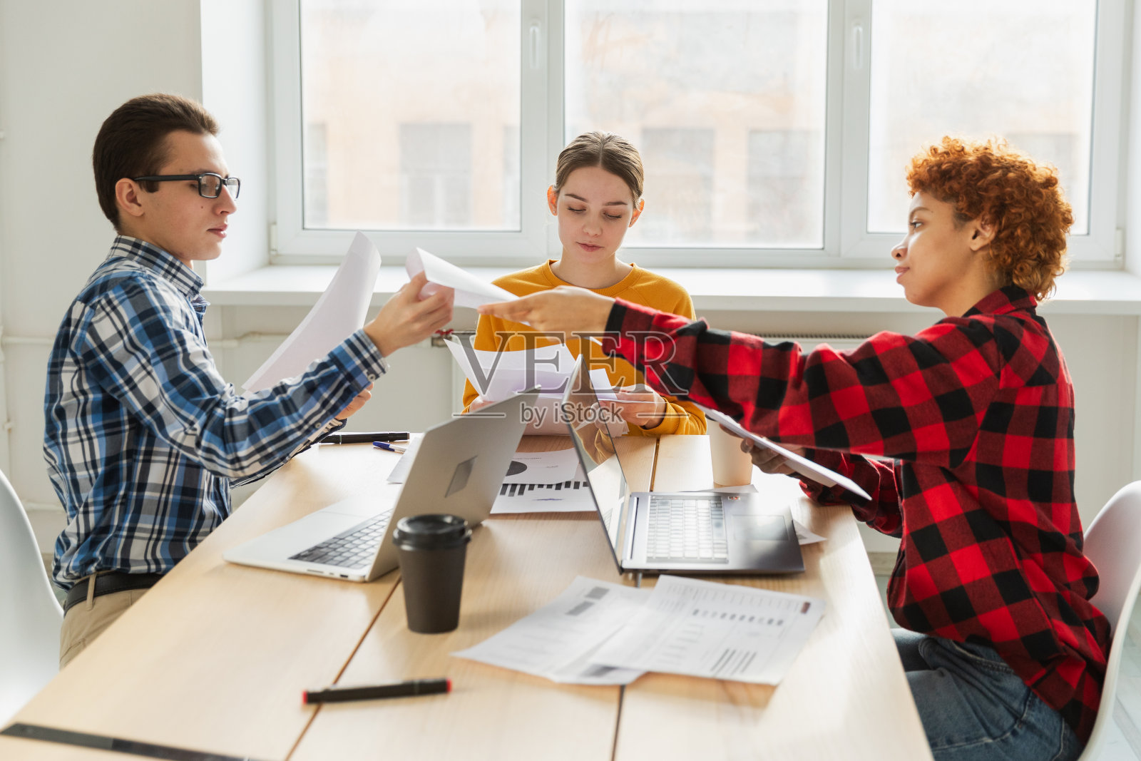 团队头脑风暴。不同的同事一起讨论金融统计。一群快乐的年轻人坐在创意办公室里讨论业务。年轻的专业团队。照片摄影图片