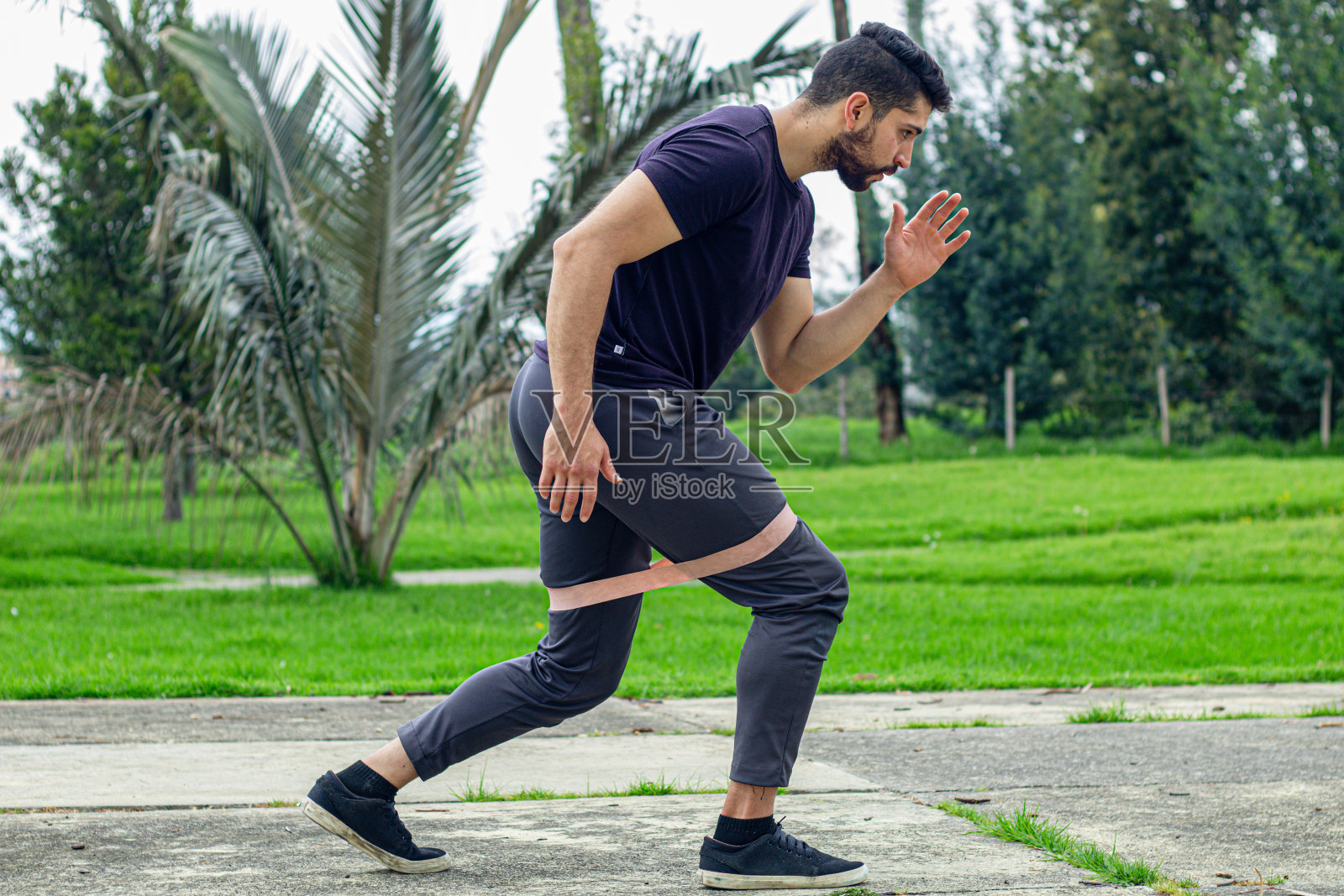 年轻人用松紧带训练,在公园户外做手臂运动照片摄影图片