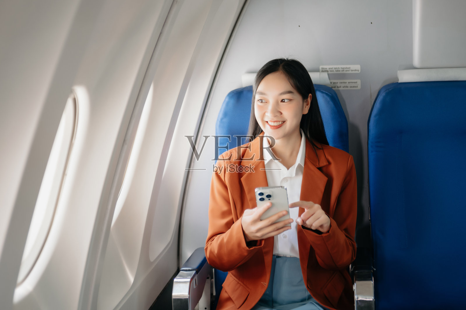 迷人的亚洲女乘客坐在舒适的座位上,同时使用笔记本电脑和平板电脑,通过无线连接模拟区域。照片摄影图片