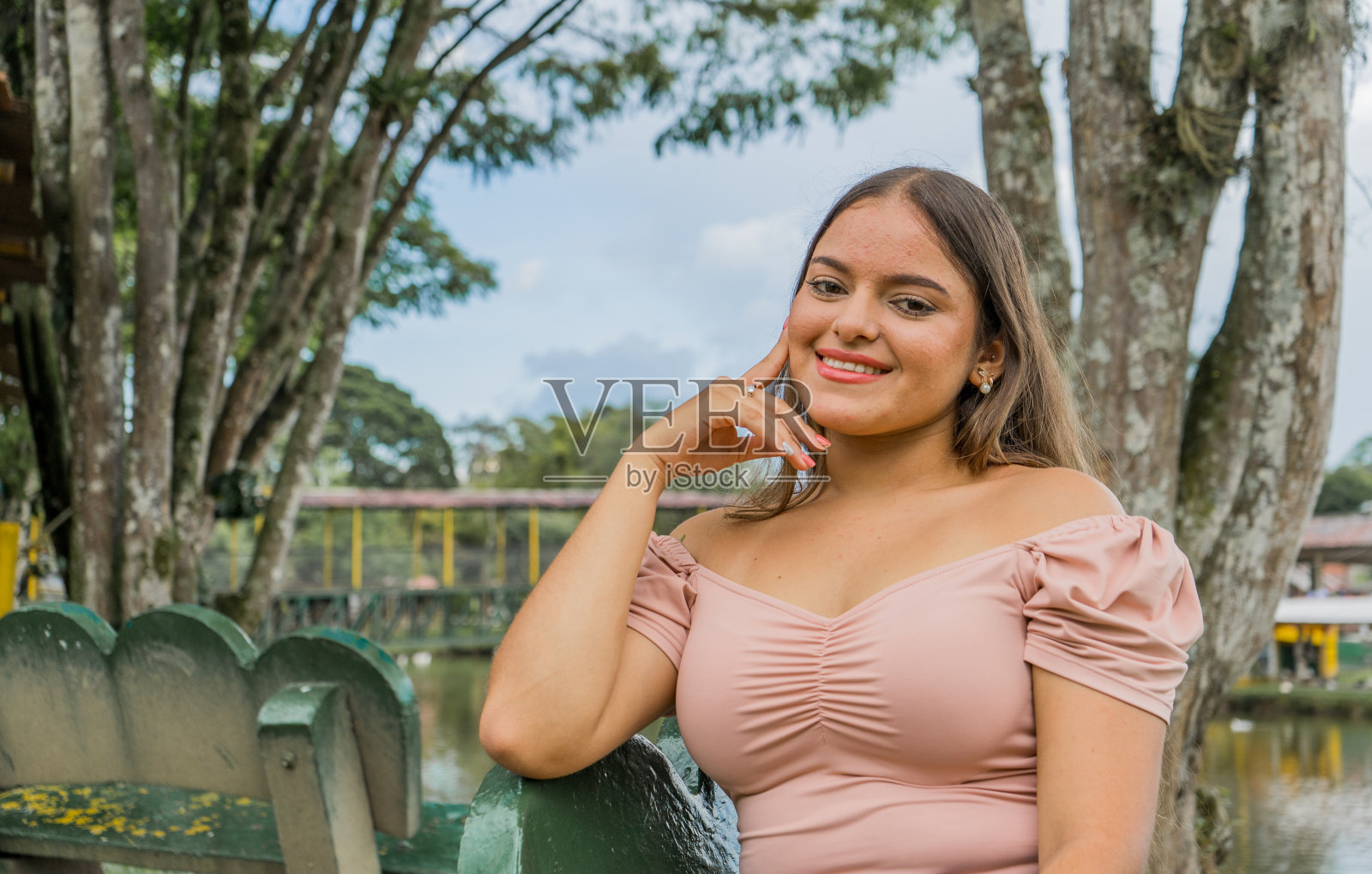 年轻女子坐在公园里,微笑着用手捂着脸照片摄影图片