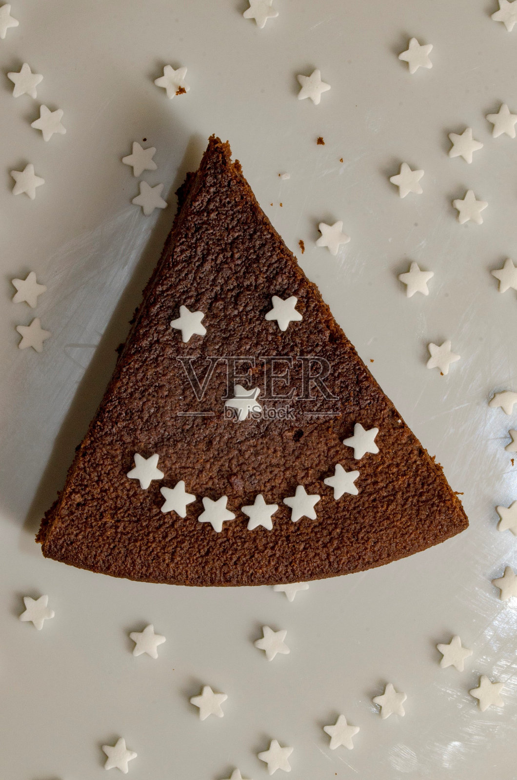 一片巧克力蛋糕,糖星星组成一个笑脸照片摄影图片