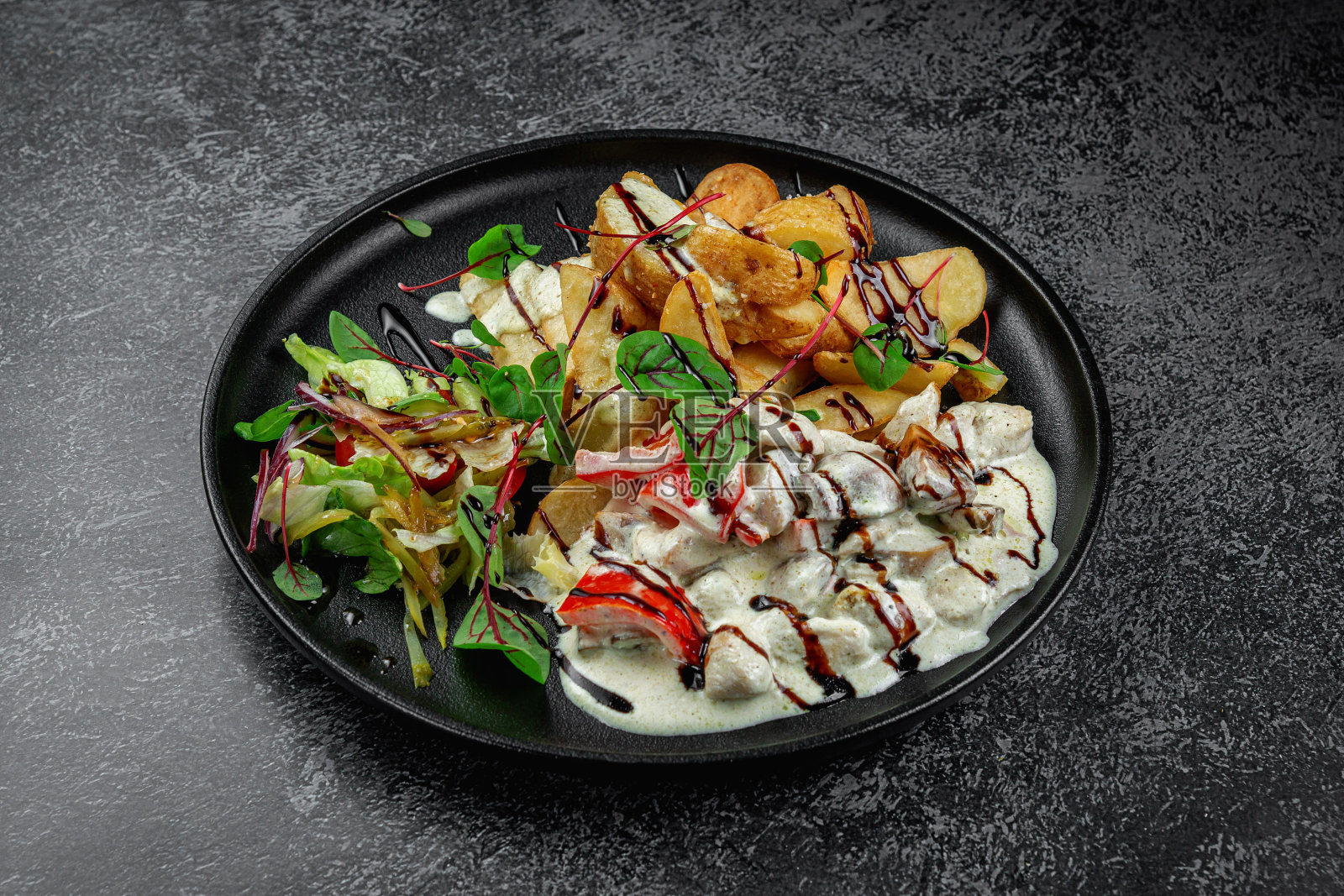 烤土豆片和炖蔬菜在奶油酱在深色盘子照片摄影图片