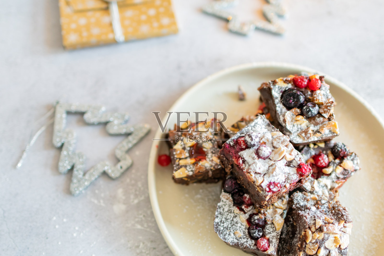 美味的自制巧克力圣诞蛋糕,上面有坚果和浆果。新鲜姜饼或可可黑蛋糕。背景是圣诞装饰的巧克力软糖布朗尼。照片摄影图片