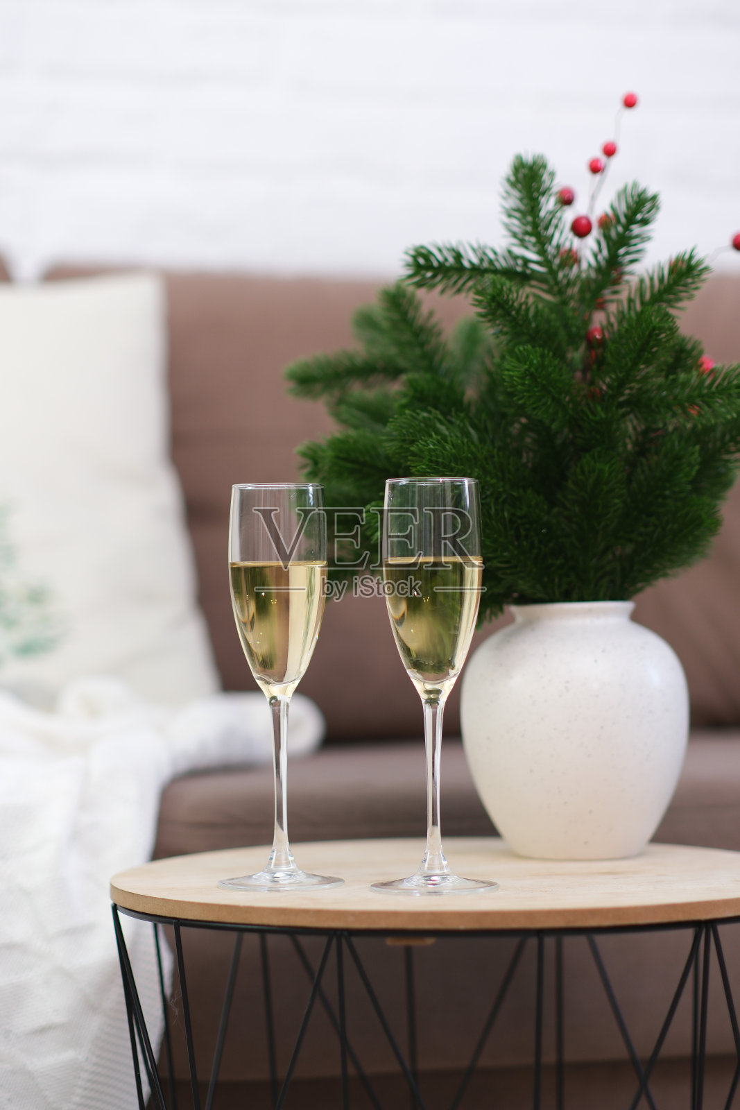 客厅咖啡桌上的两杯香槟。圣诞家庭内部。有冷杉枝的陶瓷花瓶。照片摄影图片