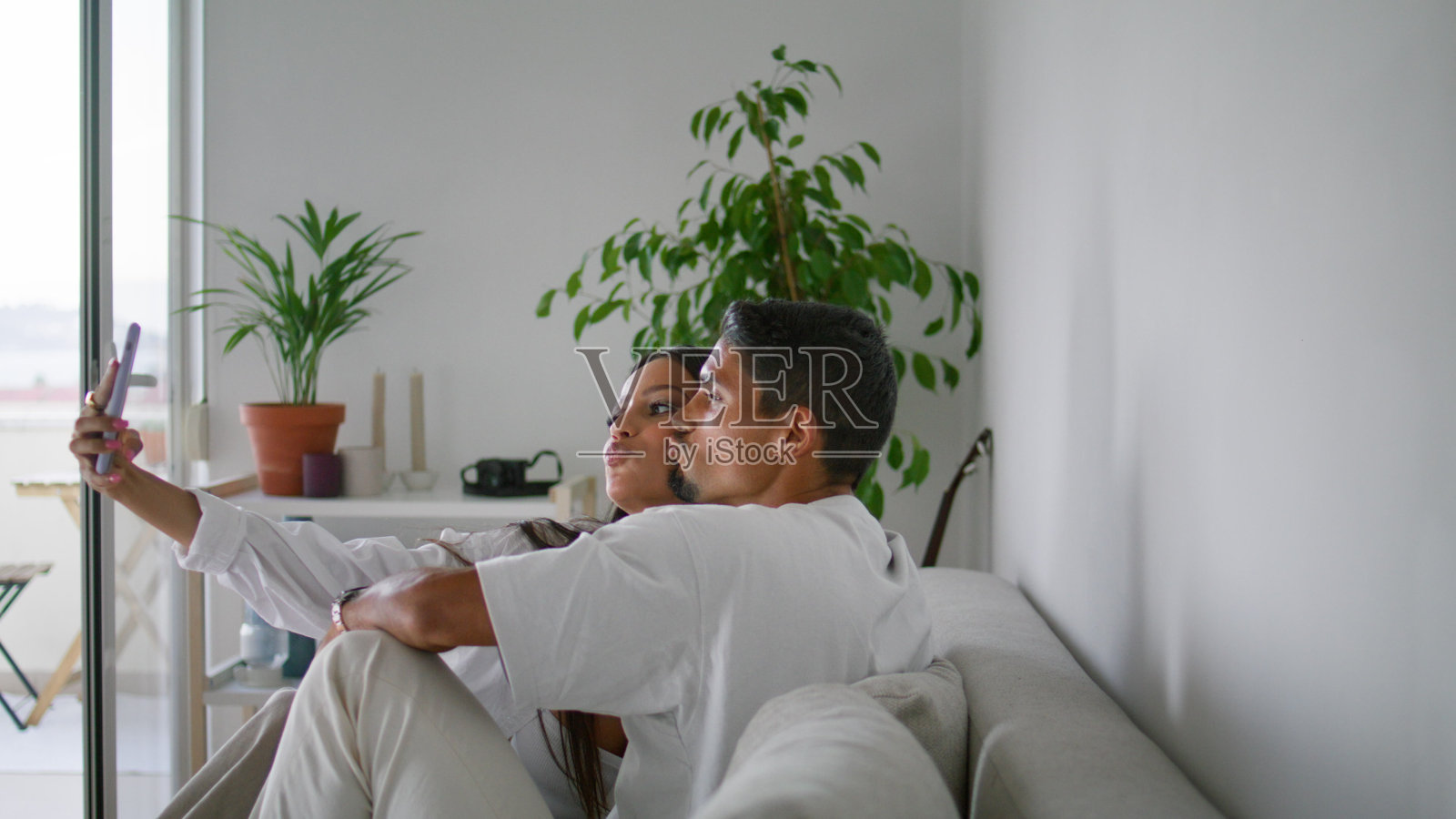 幸福的夫妇在家里拍照的特写。情侣们用智能手机自拍照片摄影图片