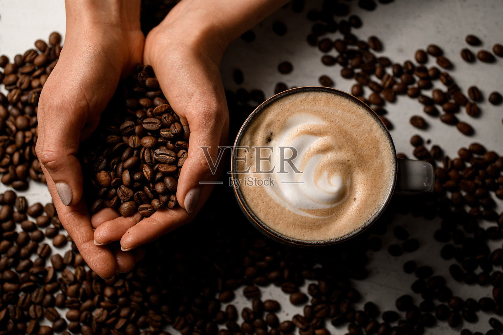 俯视图,女性的手拿着烤咖啡豆和一杯热新鲜的卡布奇诺附近照片摄影图片