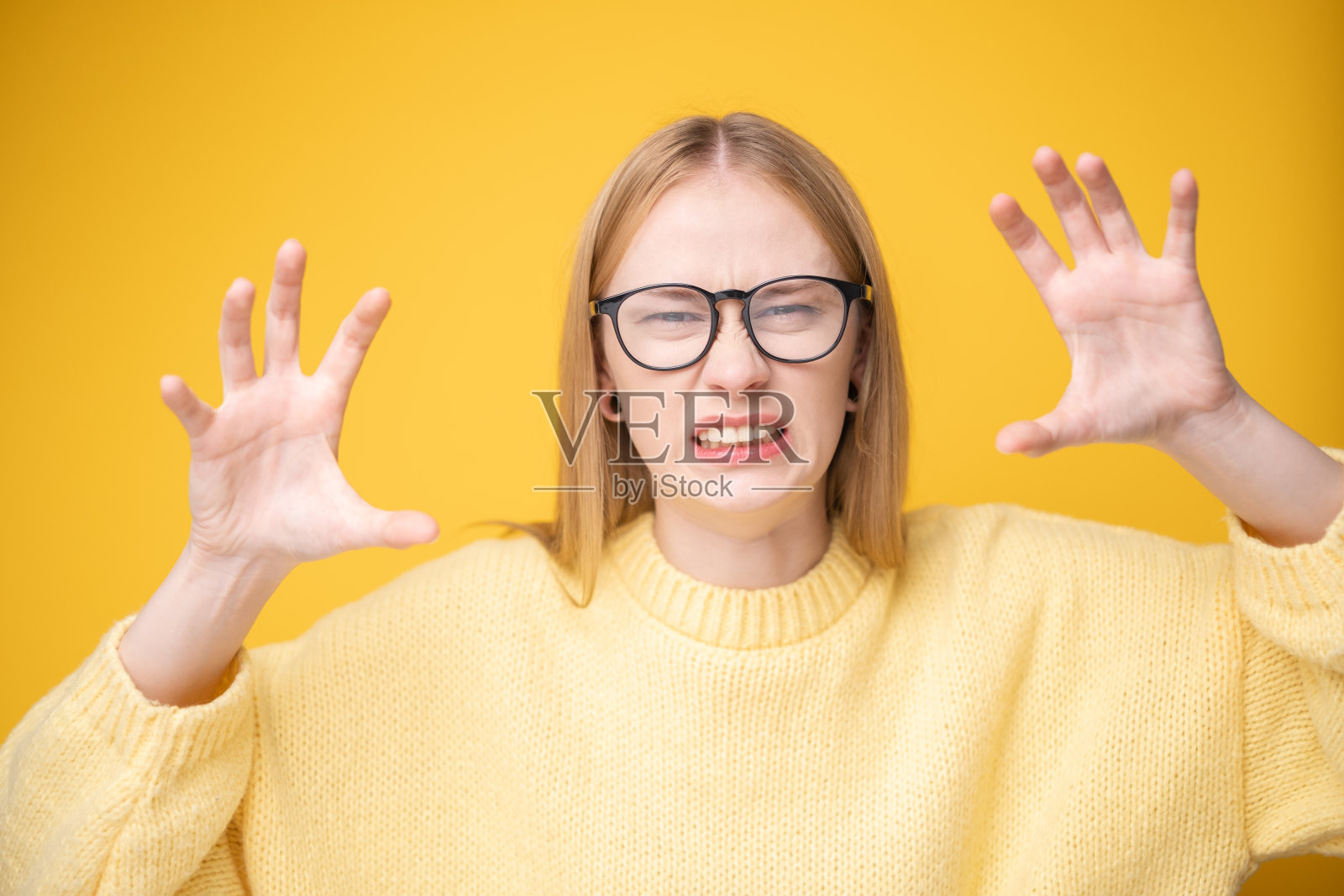 可爱的女孩在黄色背景上穿着毛衣和眼镜的肖像。横幅或广告布局。照片摄影图片