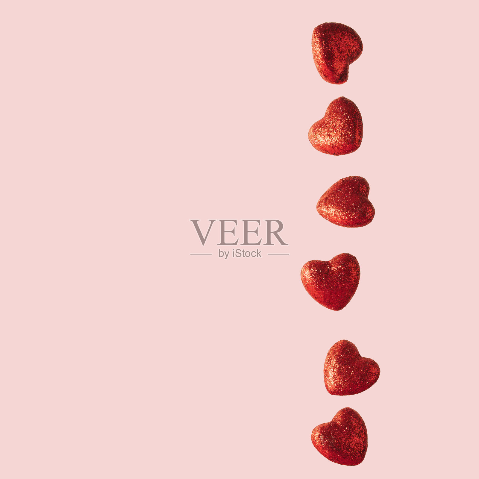 红色闪闪发光的心在柔和的粉红色背景。情人节概念。最小的组合。照片摄影图片