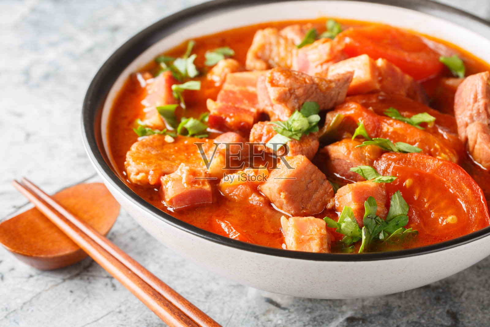 用西红柿、洋葱、甜酱油和香料在碗里炖猪肚。水平照片摄影图片