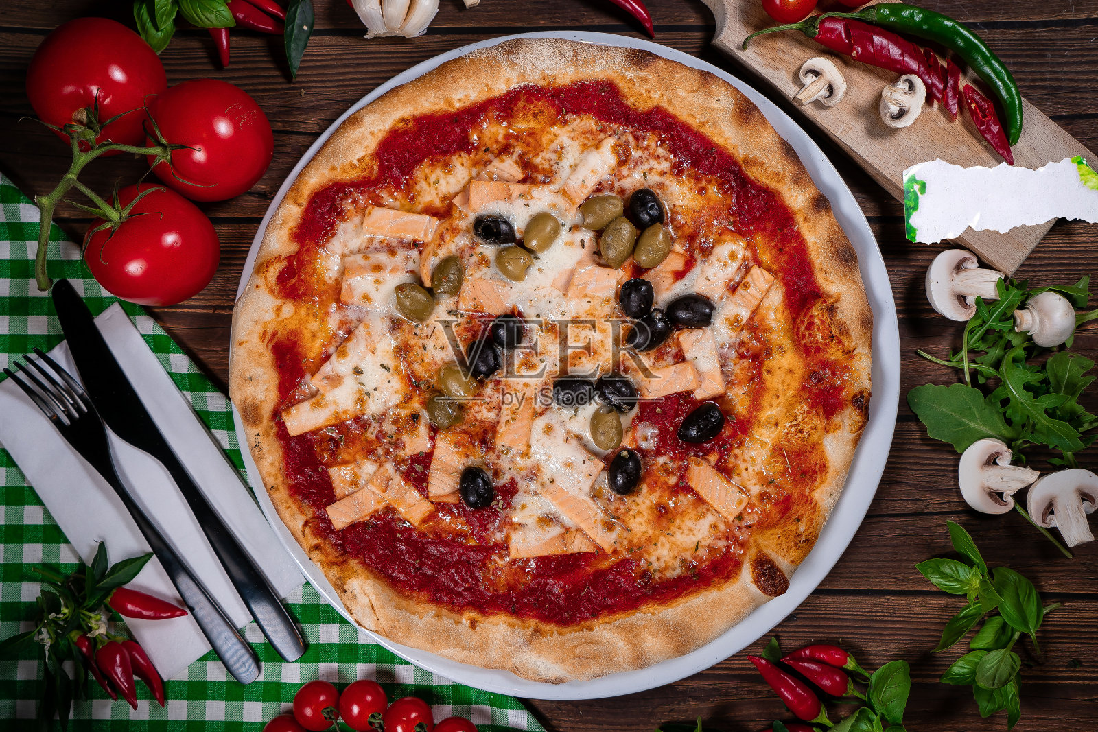 美味的热披萨,有鲑鱼,橄榄,西红柿和香料在木桌上照片摄影图片