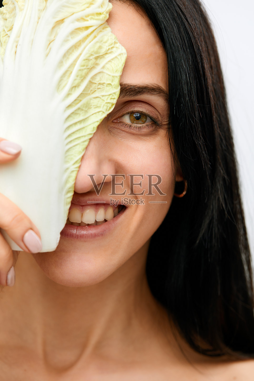 迷人的白人微笑女人的肖像,在白色的摄影棚拍摄,在眼前拿着沙拉照片摄影图片