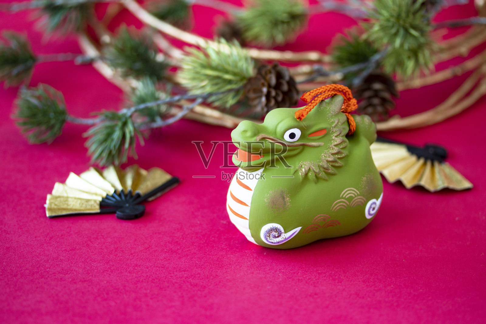 日本新年的龙年,生肖的象征在红色的背景与复制空间。用金扇和水木和假松。照片摄影图片