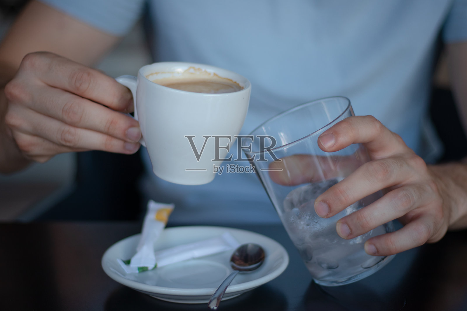 一个年轻人拿着一杯咖啡和一个加冰的杯子照片摄影图片