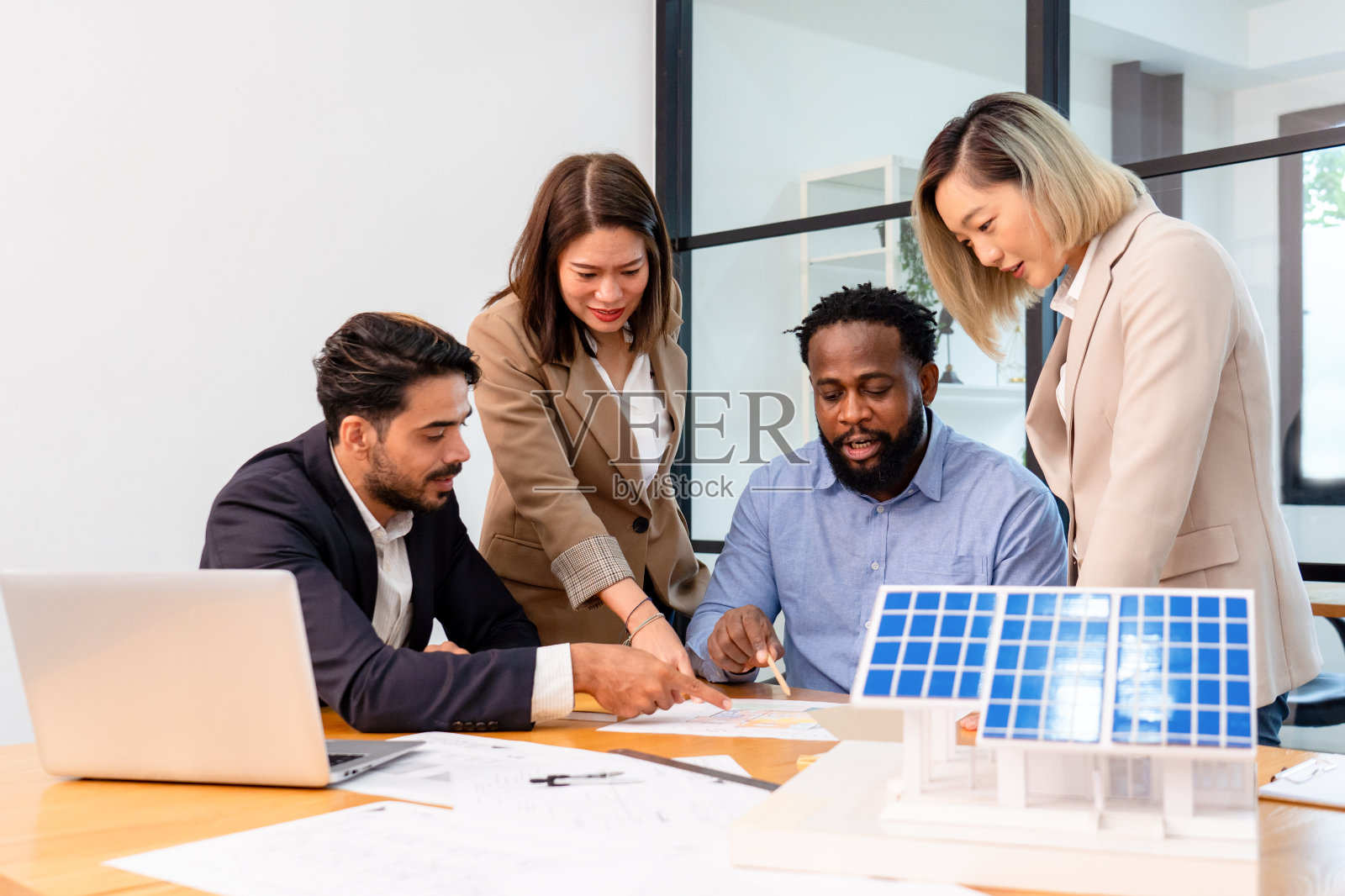 多民族同事开会讨论太阳能屋顶系统项目和太阳能板房屋模型照片摄影图片