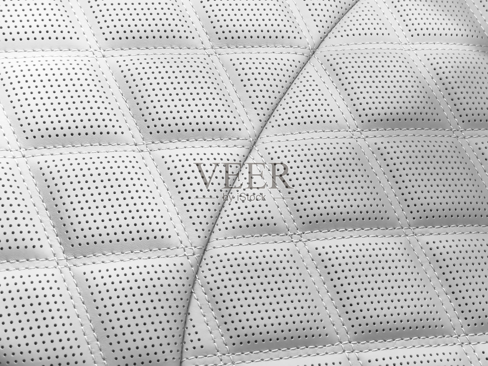 汽车白色皮革内饰。穿孔皮革汽车座椅细节的一部分。白色穿孔皮革纹理背景。质地:人造革带缝线。穿孔的座位照片摄影图片