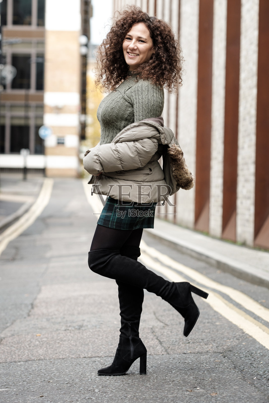 微笑的成熟卷发女子在伦敦的城市街道上摆姿势。照片摄影图片