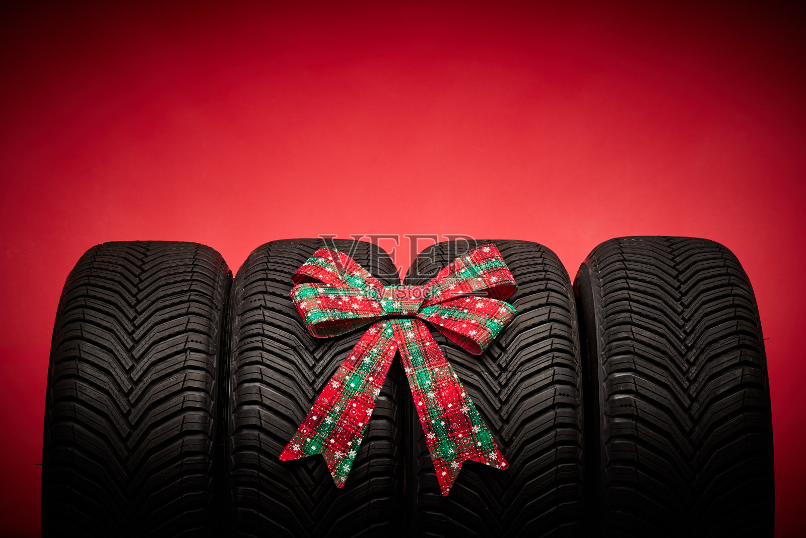 汽车轮胎,新轮胎,冬季车轮孤立的红色圣诞背景与蝴蝶结丝带。照片摄影图片