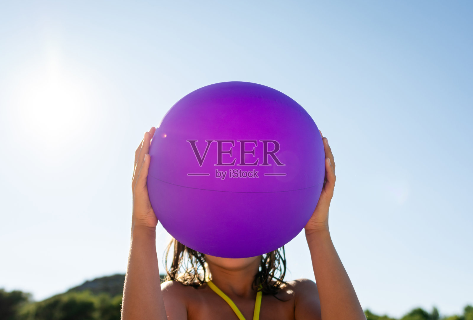 女孩拿着沙滩球在她的头顶对着蓝天照片摄影图片