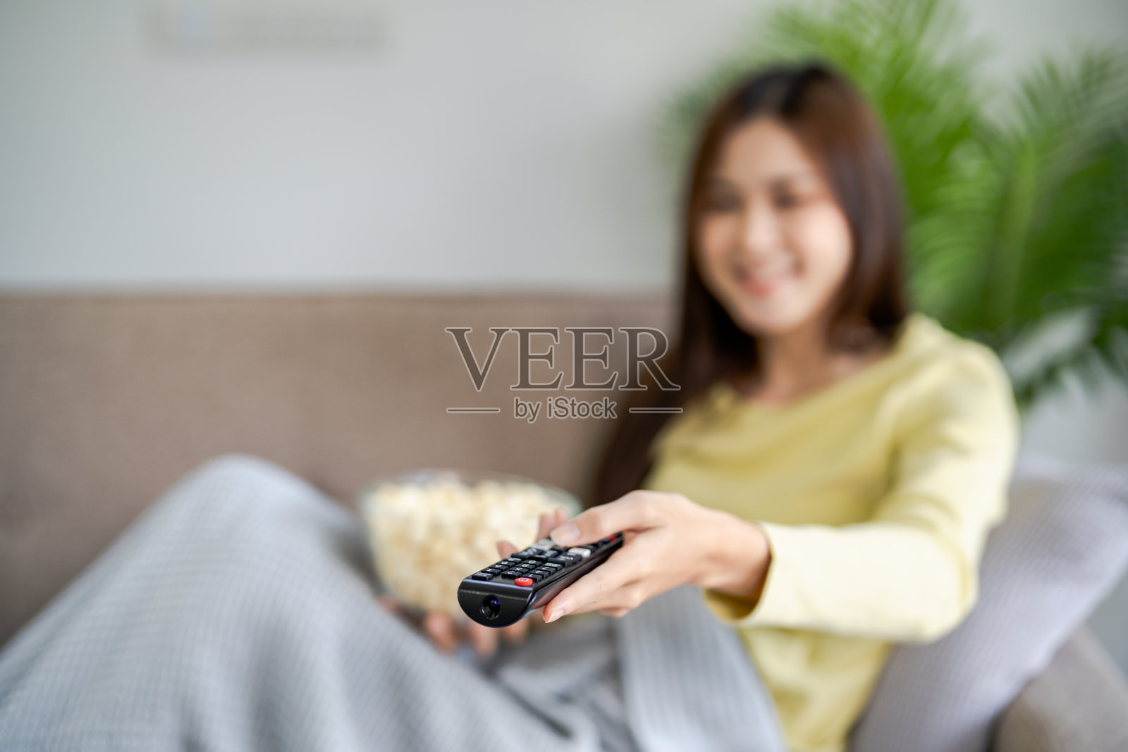 亚洲女性观看智能电视和使用遥控器手持电视音频遥控器在家里用遥控器控制电视照片摄影图片