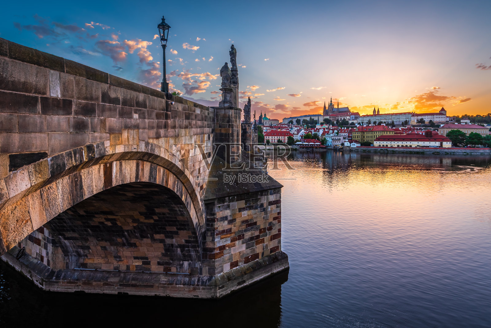 联合国教科文组织世界遗产查尔斯大桥和布拉格城堡在夏至日,当太阳落在城堡后面。照片摄影图片