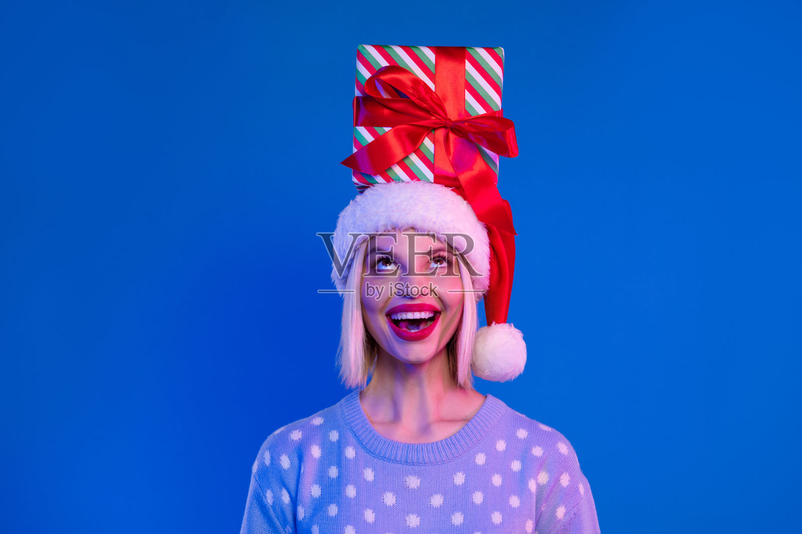 照片的开朗漂亮迷人的女孩穿着时髦的装饰品看孤立的蓝色背景照片摄影图片