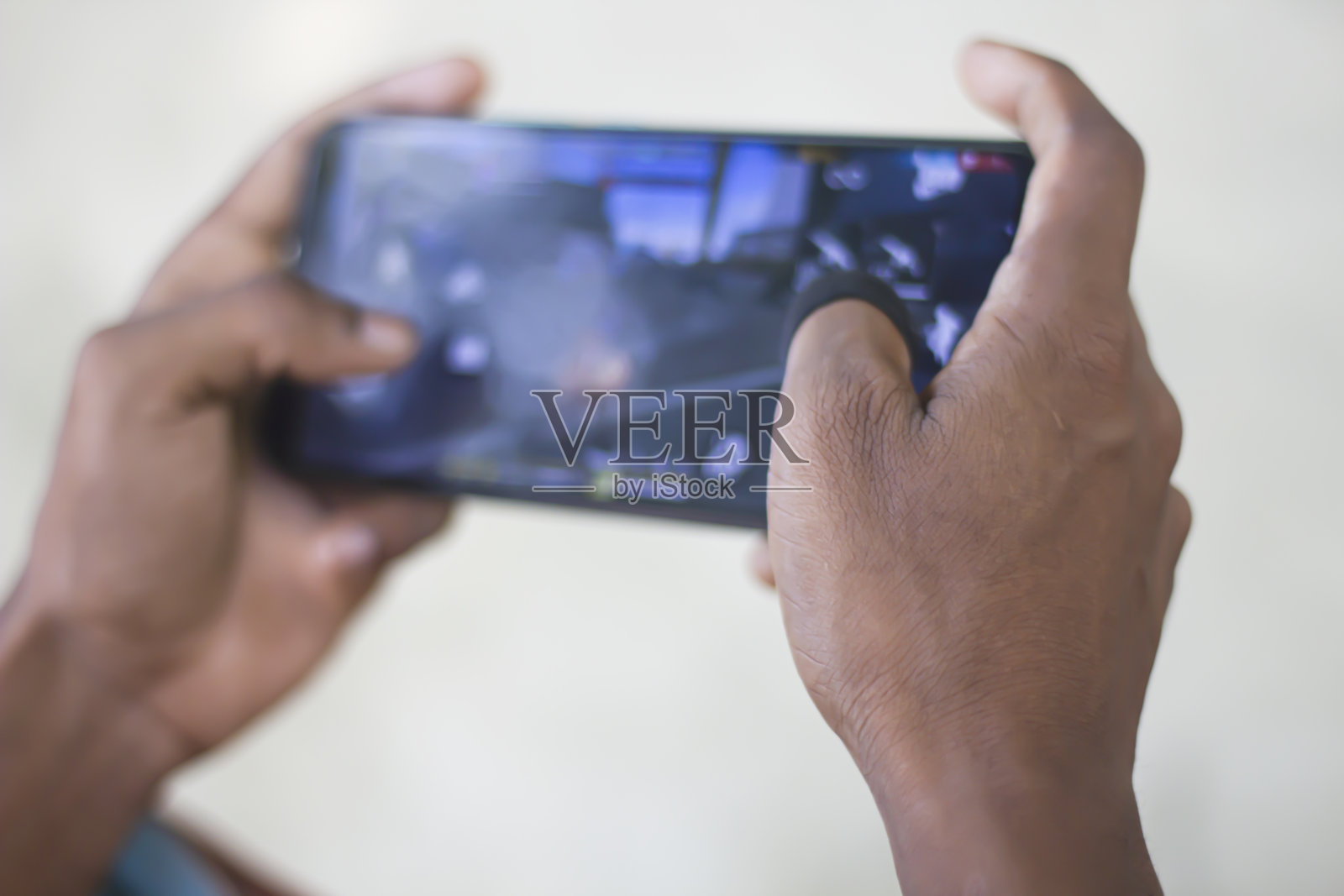 一名男子在手机上玩游戏,背景模糊照片摄影图片