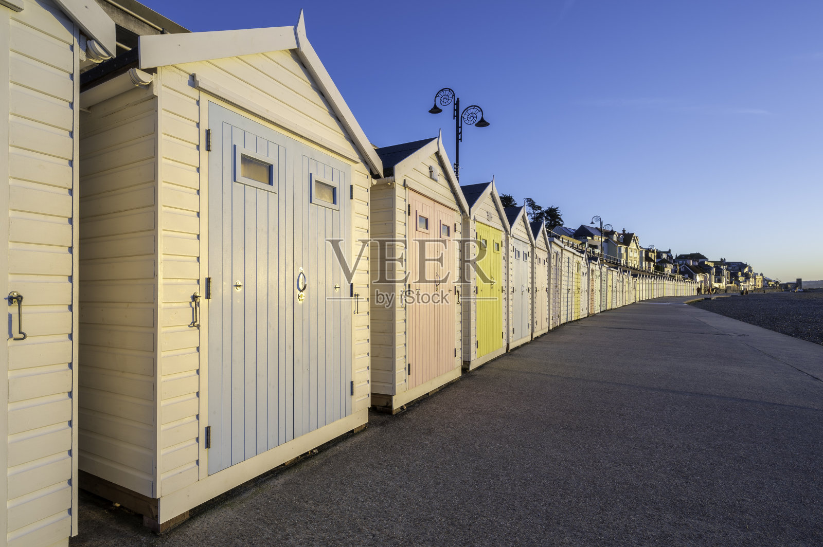 色彩缤纷的海滩小屋,在夏日蔚蓝的天空衬托下,一直延伸到远处。地点是莱姆里吉斯,英格兰南部海岸照片摄影图片