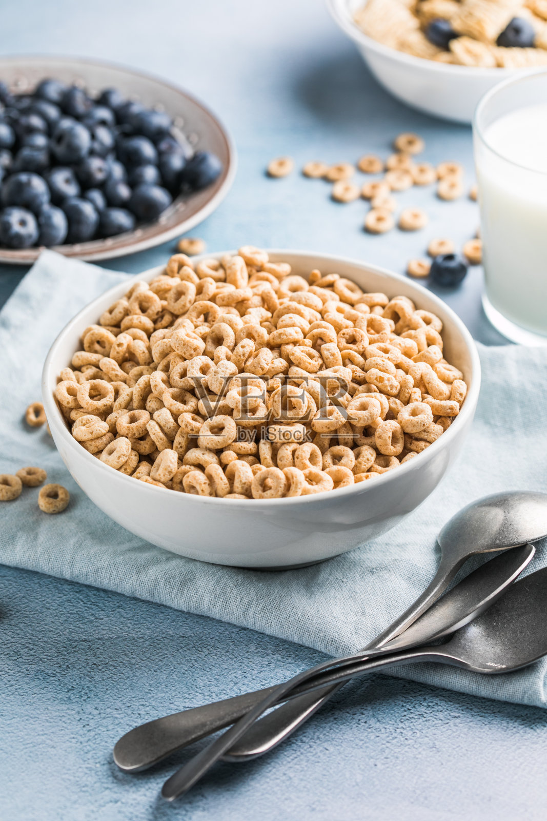 健康早餐的概念是素食酸奶,全谷物谷物新鲜水果放在蓝色的桌子上,白色的厨房背景。前视图。照片摄影图片