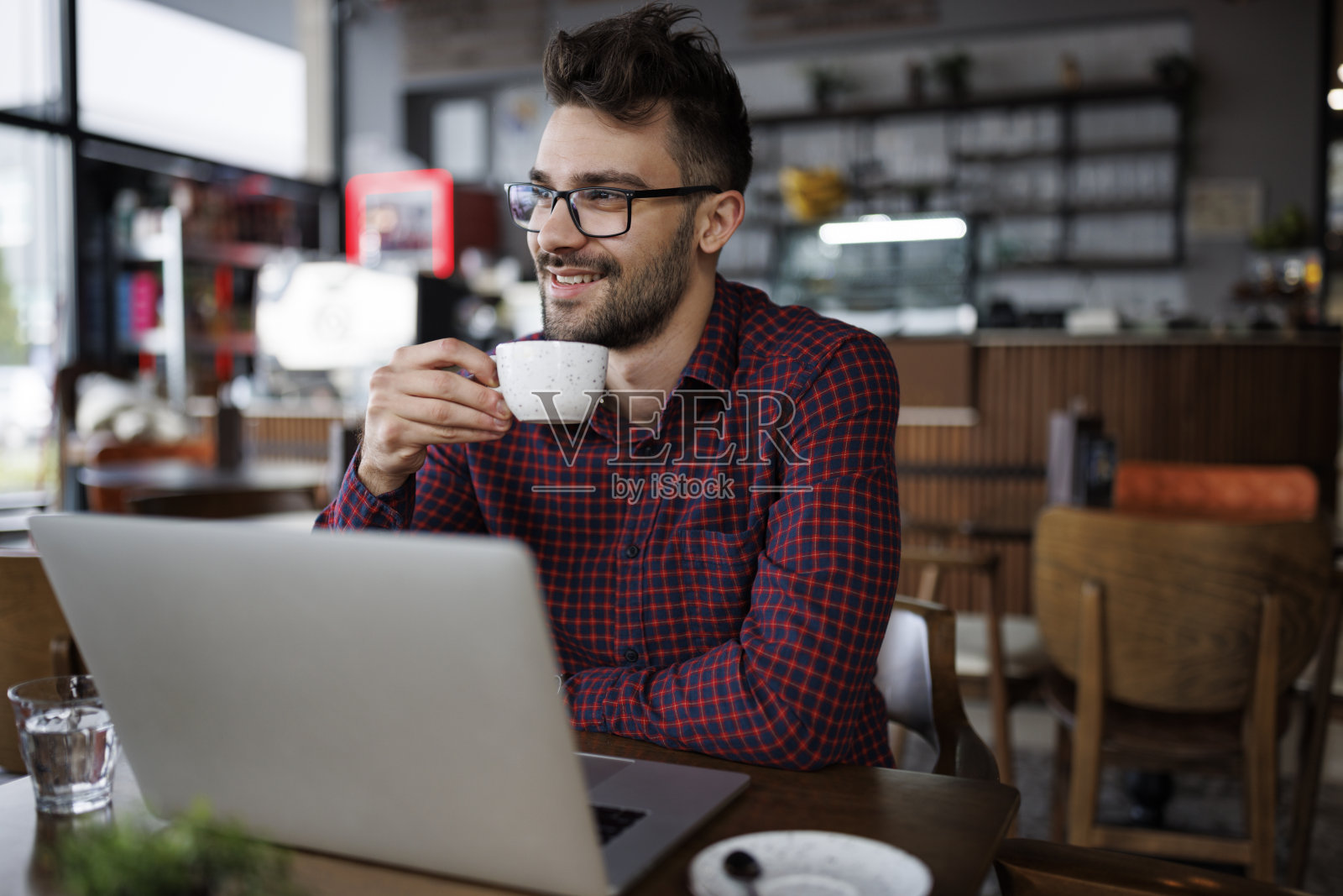微笑的年轻人在咖啡馆喝咖啡和使用笔记本电脑照片摄影图片