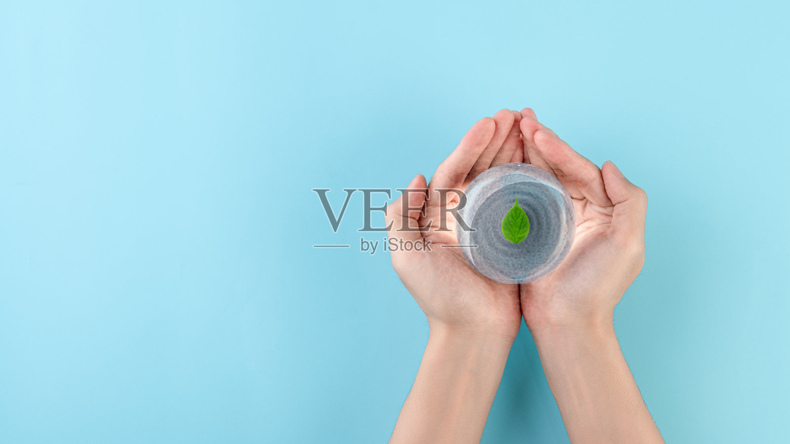 拿一个玻璃球,里面有水,上面有树叶,世界水日,节约用水,清洁可再生能源,防洪救灾的理念。照片摄影图片