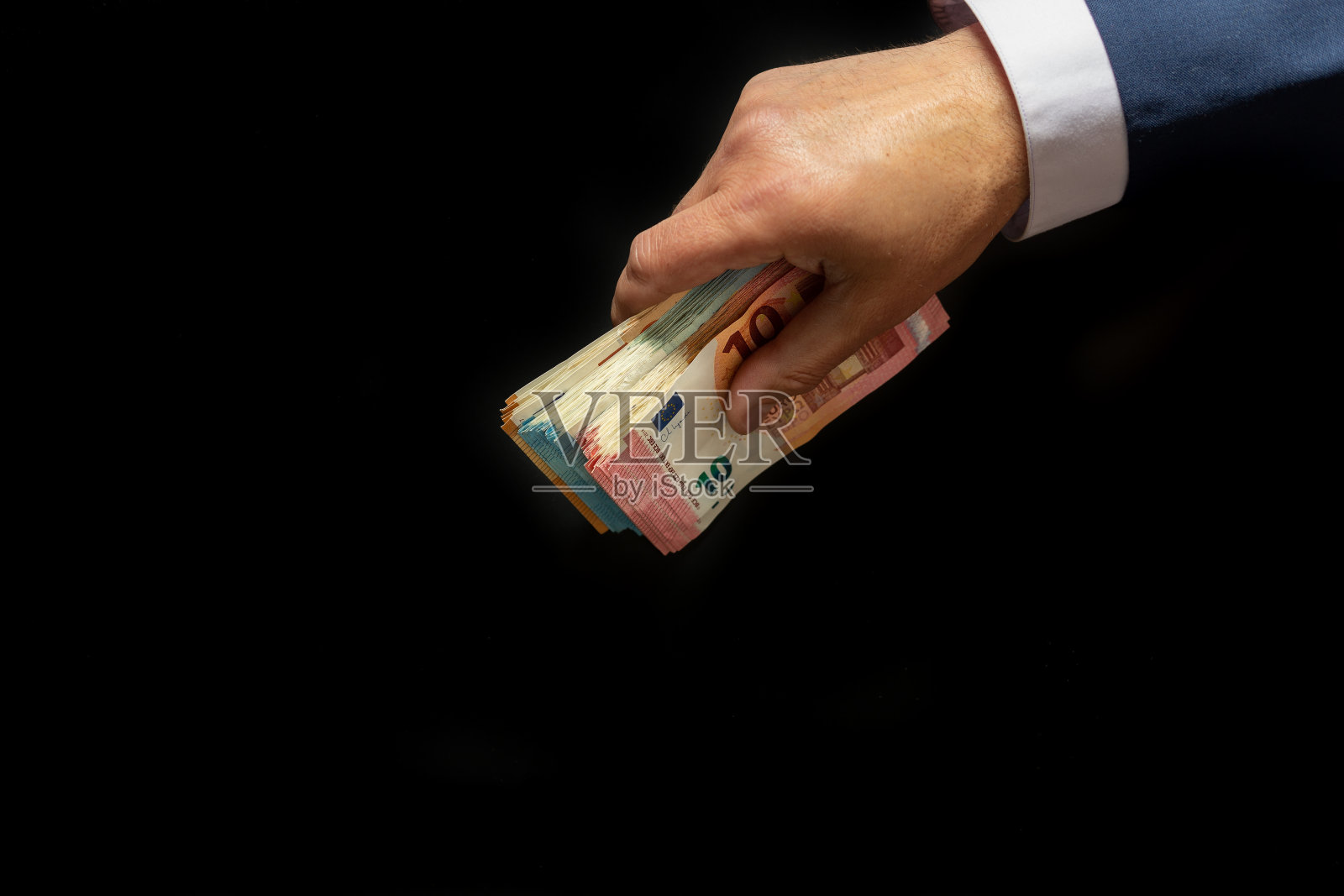 一个商人修剪整齐的手,拿着一捆钞票,好像想把它藏起来。照片摄影图片