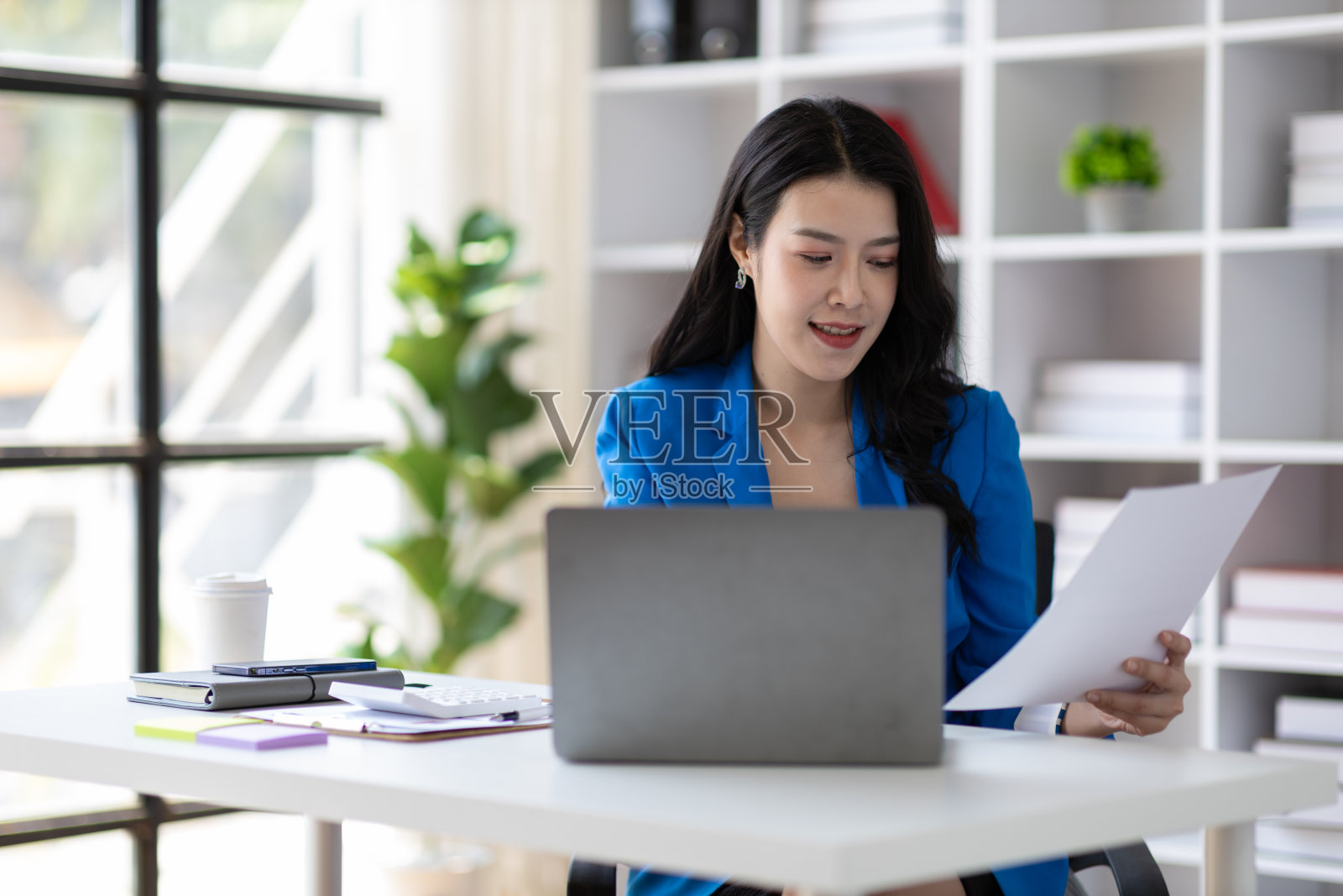 迷人的亚洲女商务秘书,在办公室里用笔记本电脑和文书工作。照片摄影图片