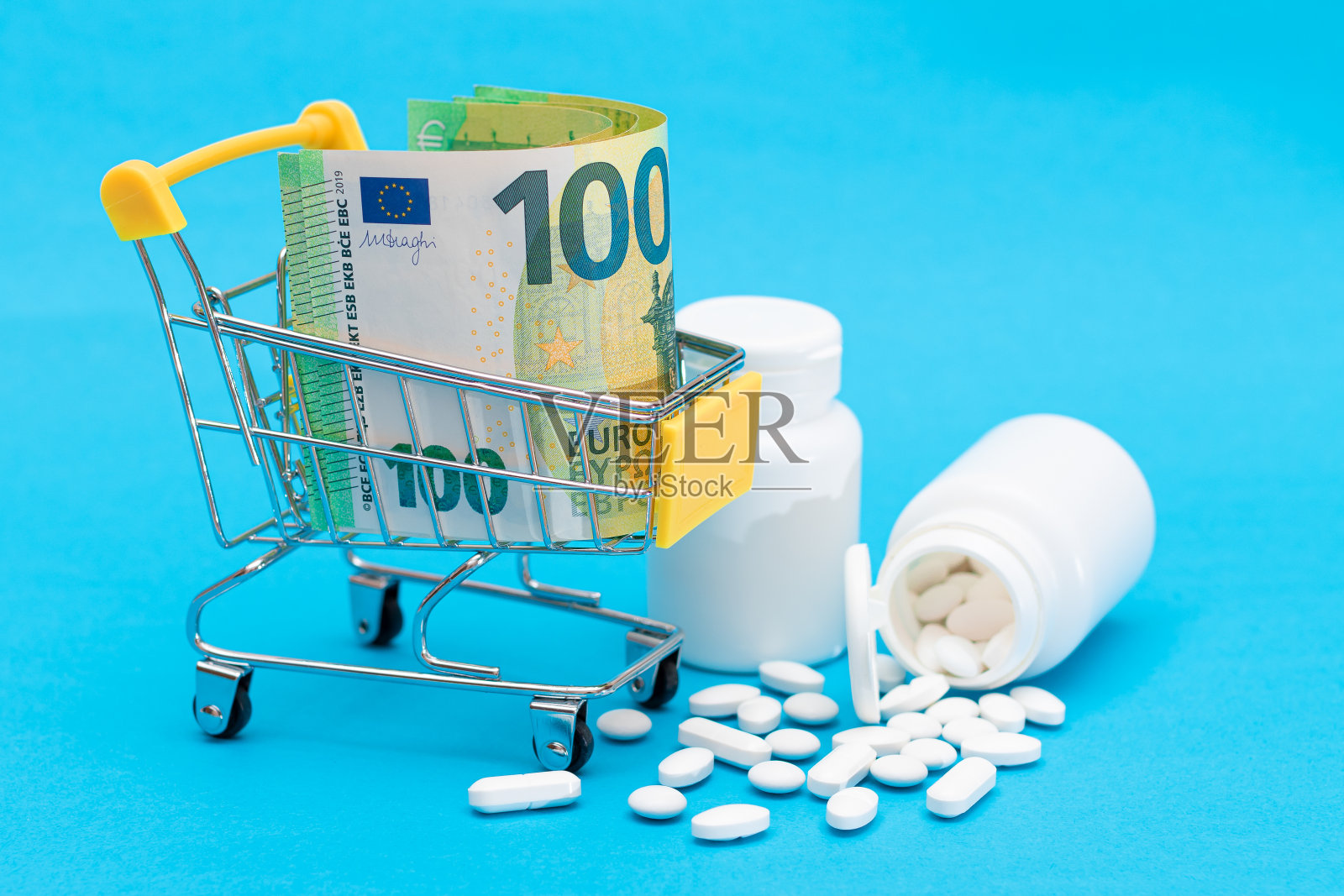 散落的药丸或胶囊和购物车在蓝色背景照片摄影图片