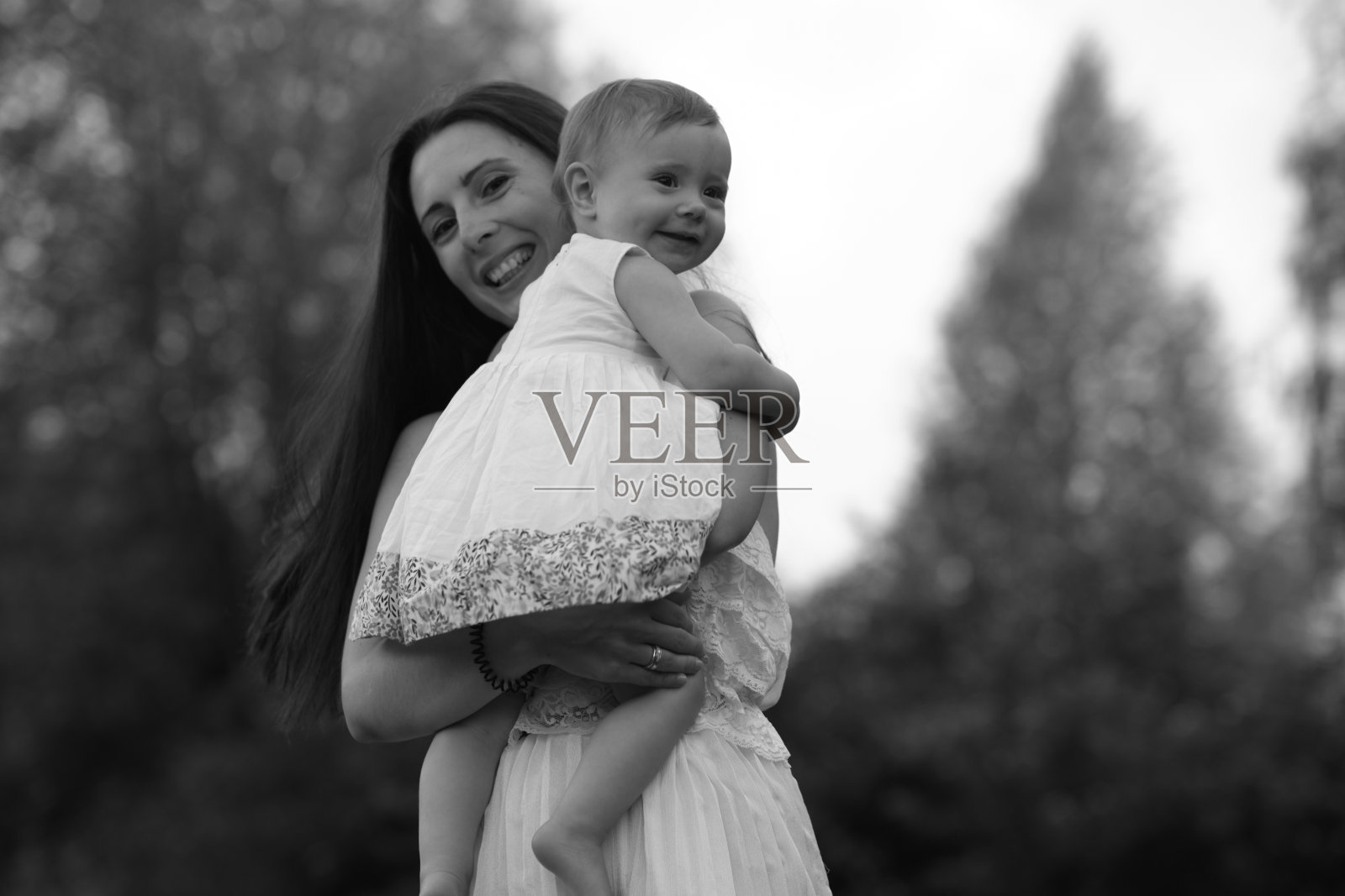 在妈妈的怀里,一个婴儿在咯咯地笑;母爱和生活中简单快乐的快照。照片摄影图片