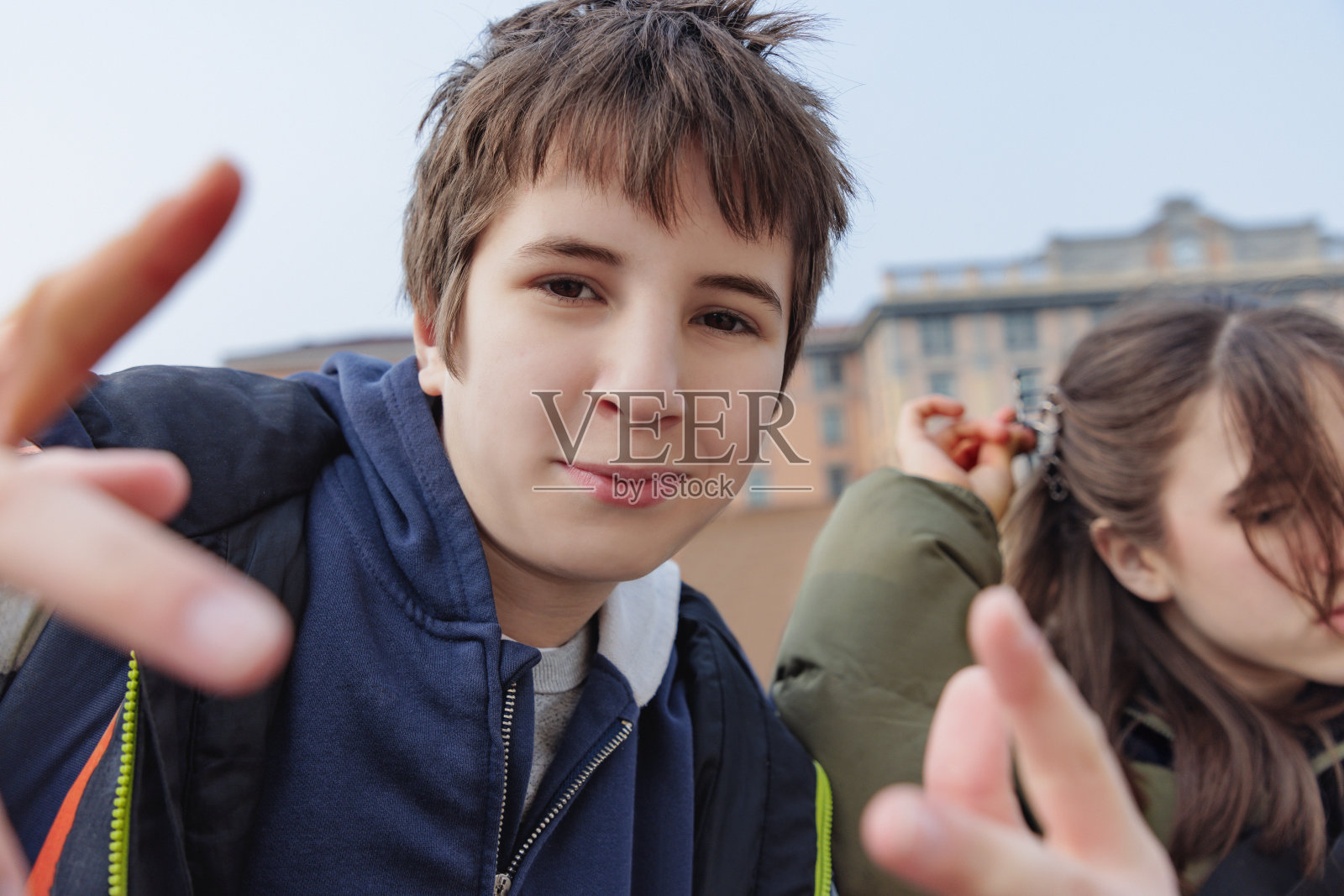 青春期前的男孩站在妹妹身边,对着镜头打手势,一家人去意大利旅游照片摄影图片
