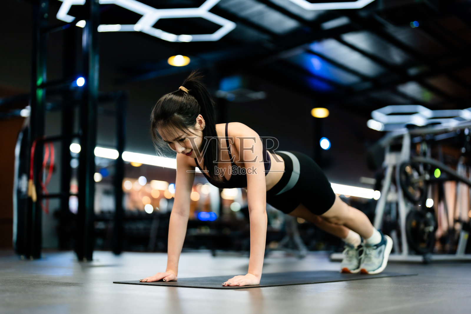 年轻的亚洲女子在健身中心练习平板支撑。健康健美的理念照片摄影图片