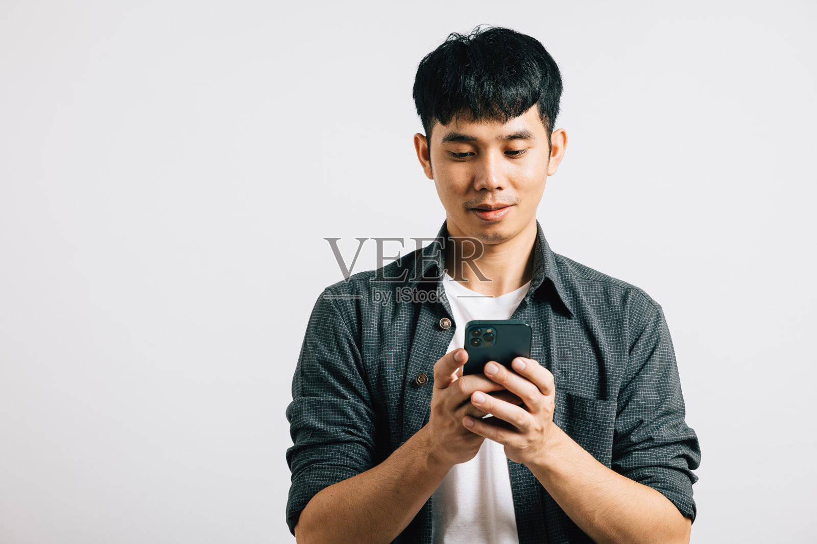 一名亚洲少年兴奋地在他的智能手机上输入短信进行在线交流照片摄影图片