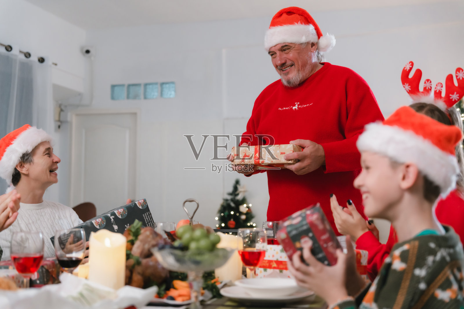 一个家庭在装饰过圣诞节的房间里的许多桌子上庆祝。交换礼物玩得开心照片摄影图片