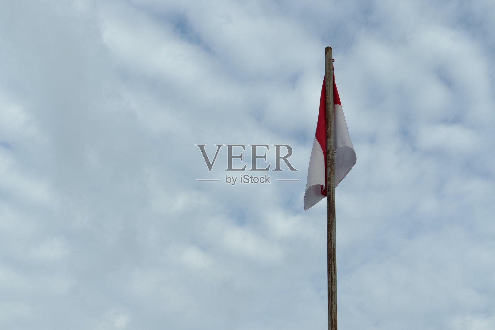 印度尼西亚国旗是红白相间的,背景是多云的蓝天照片摄影图片