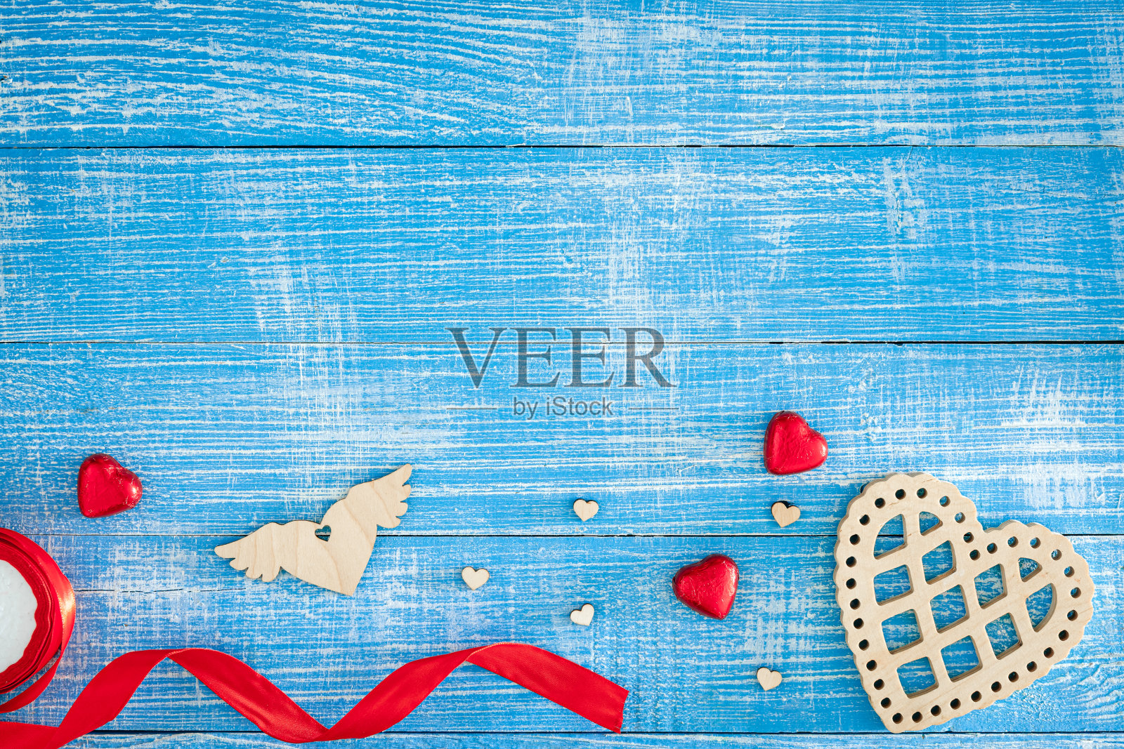 木制心形和红色糖果在木制蓝色背景上,俯视图。照片摄影图片