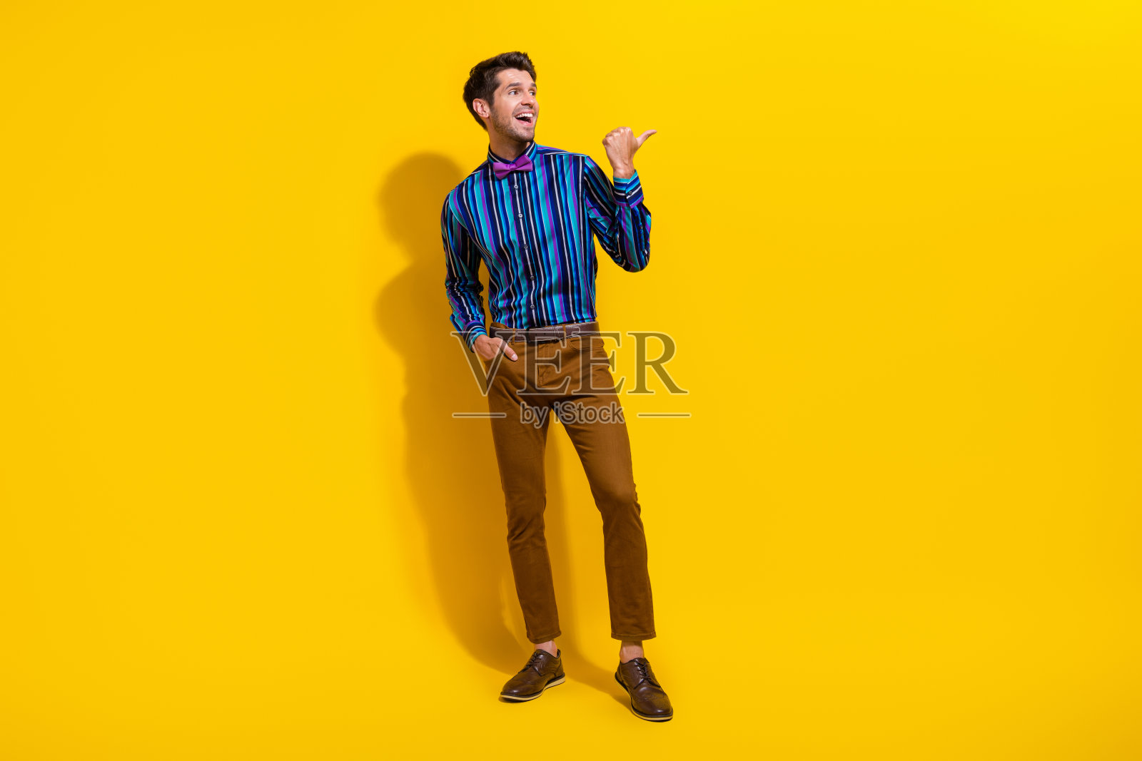 印象深刻的家伙穿着条纹衬衫的全尺寸照片,看着惊人的黄色背景上孤立的空白空间照片摄影图片