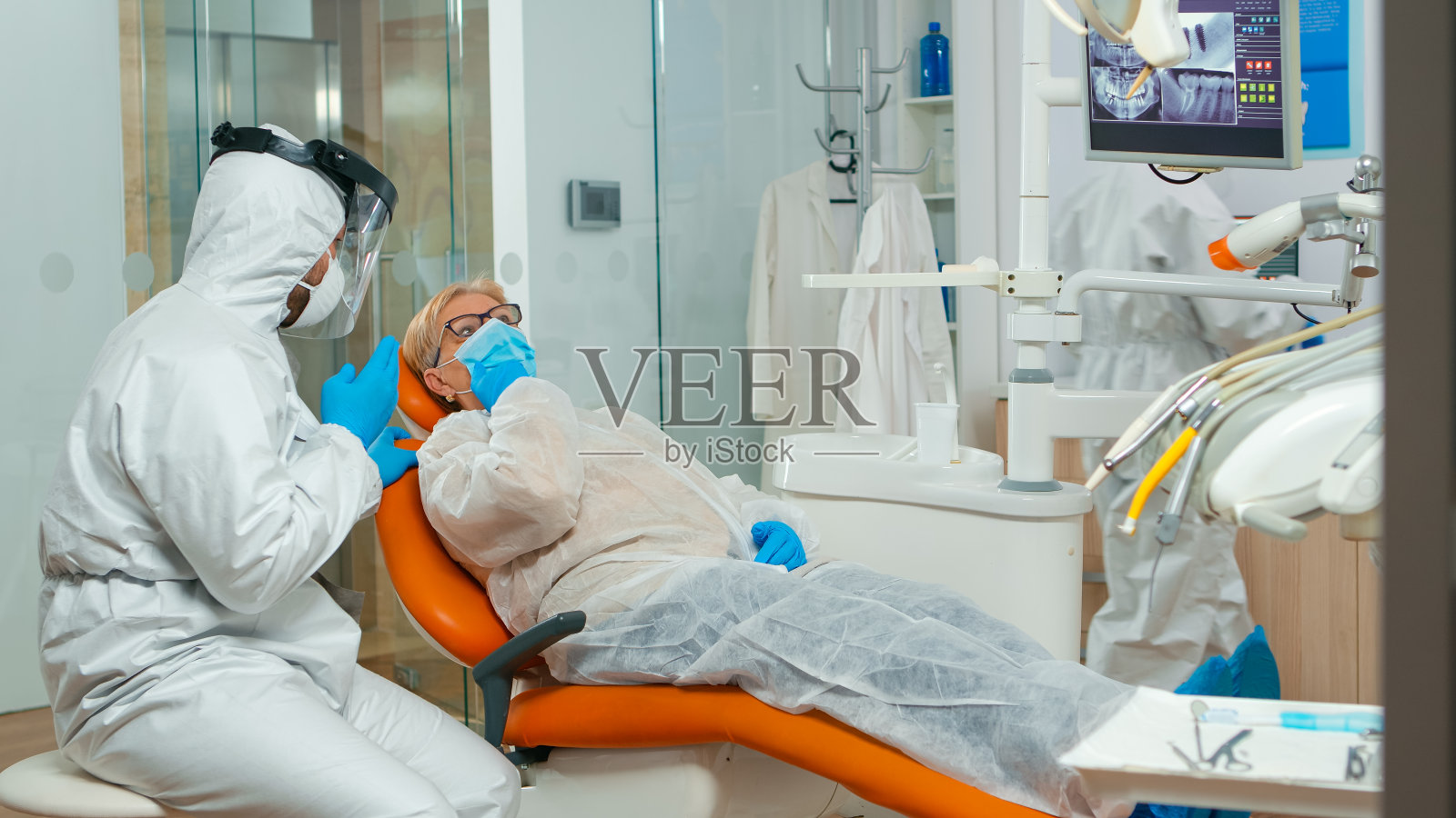 穿着防护服的正畸医生与牙痛患者交谈照片摄影图片