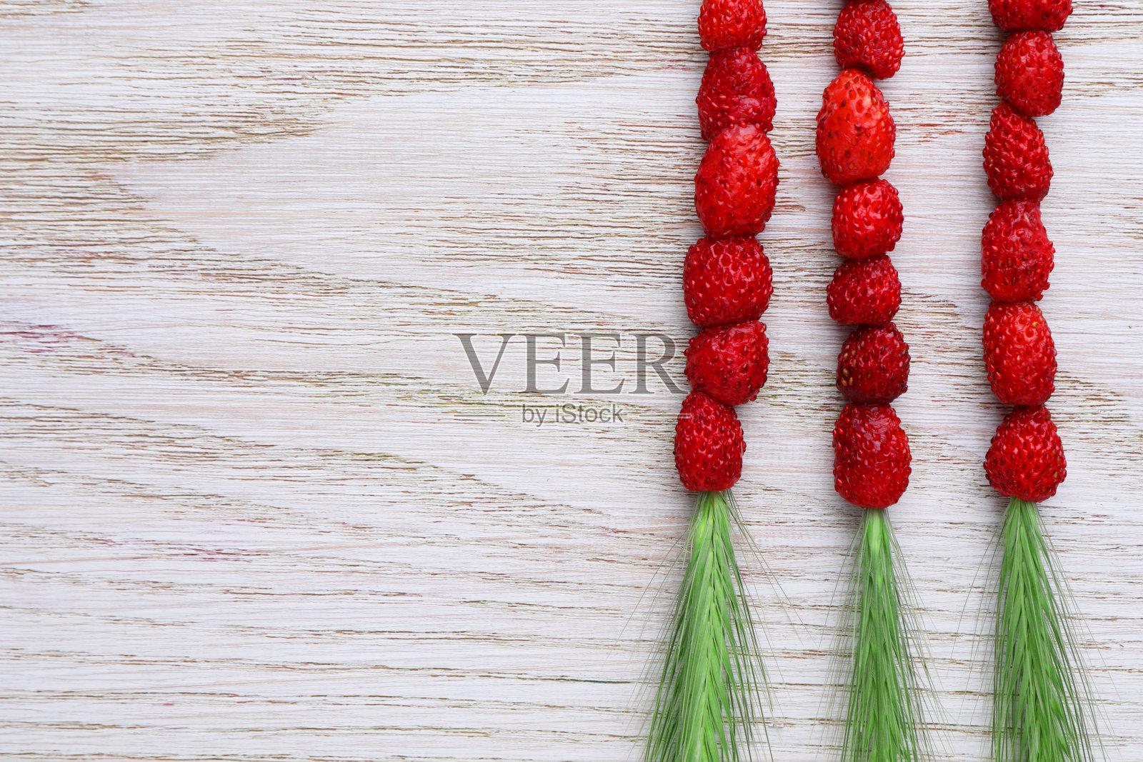 草茎与野草莓放在白色的木桌上,平躺着。文本空间照片摄影图片