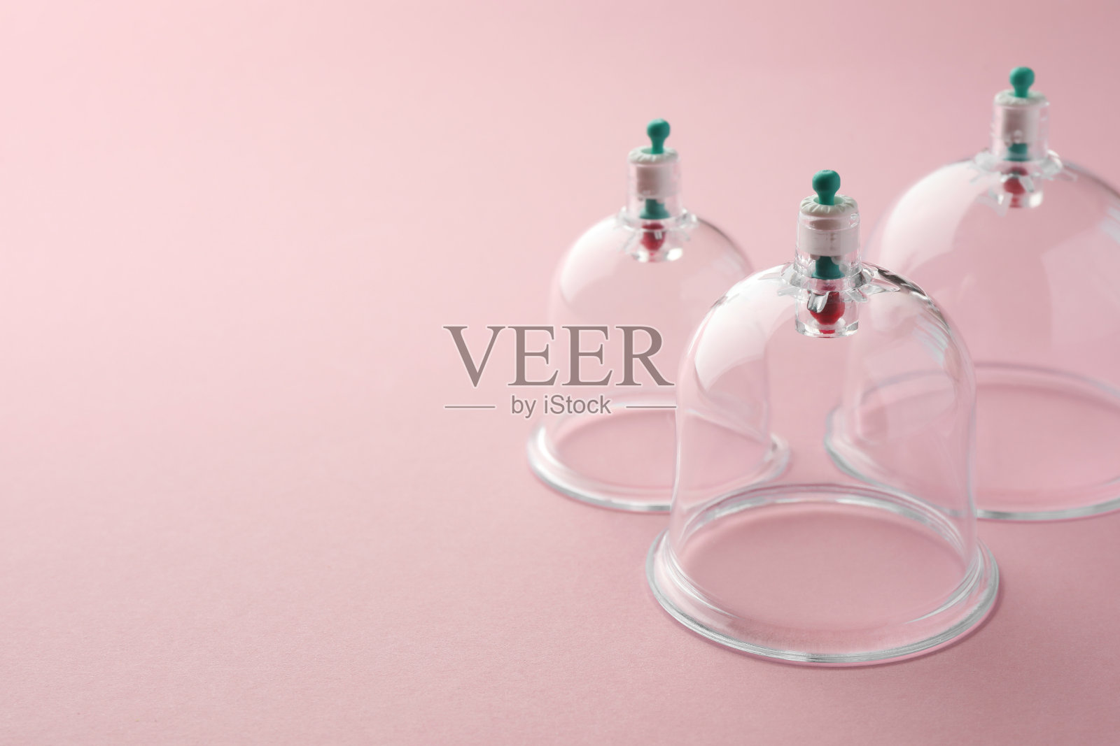 粉色背景的塑料杯,留出文字空间。拔火罐照片摄影图片